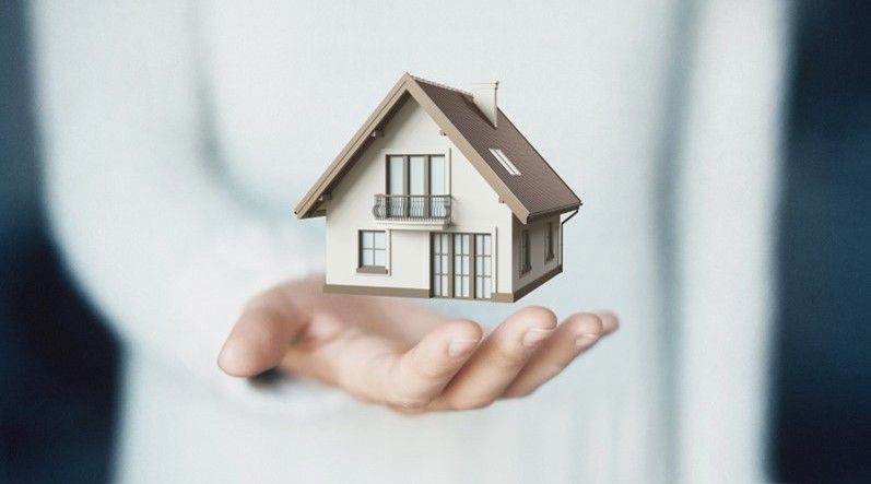 A person is holding a model house in their hand.