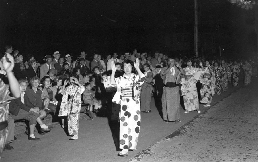 Crowd dancing outdoors at night, with one person in a polka-dot costume in the foreground