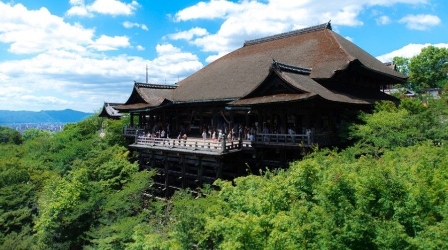 Kiyomizu-Dera Temple surrounded by lush green trees under a blue sky