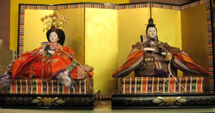Japanese Hina dolls, seated figures, in elaborate robes, gold screen background.