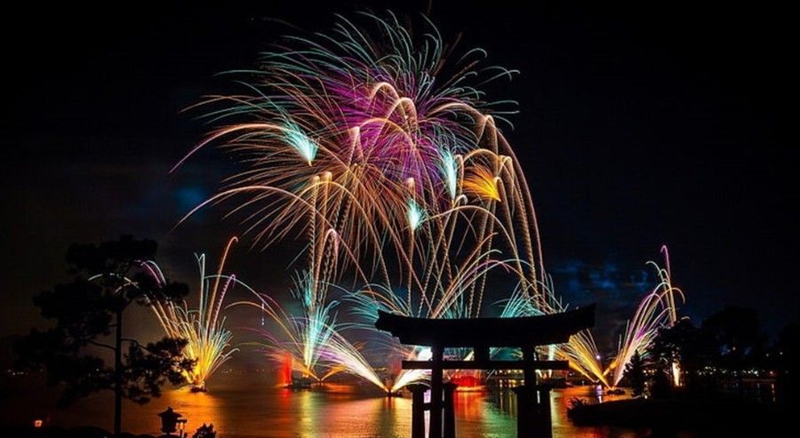 Fireworks are displayed over a torii gate at night