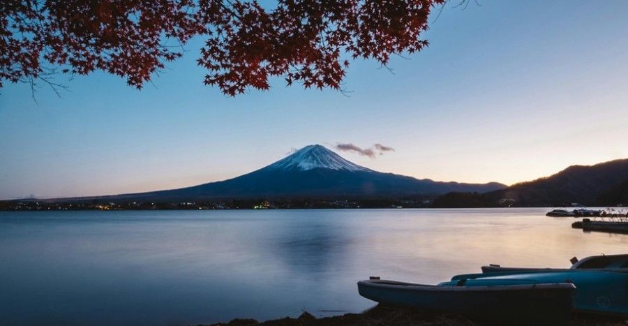 A lake with Mt. Fuji in the background and boats in the foreground.