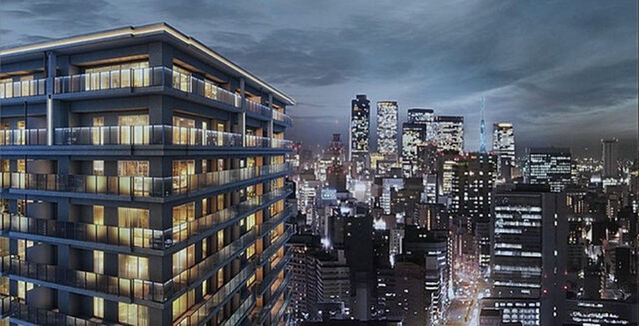 Night cityscape: lit modern building, overlooking Nagoya city lights under a cloudy sky.