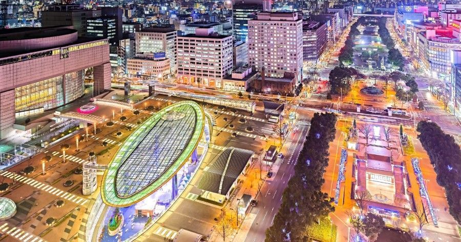 Nighttime aerial view of Nagoya with illuminated buildings and a large oval structure (Oasis21).
