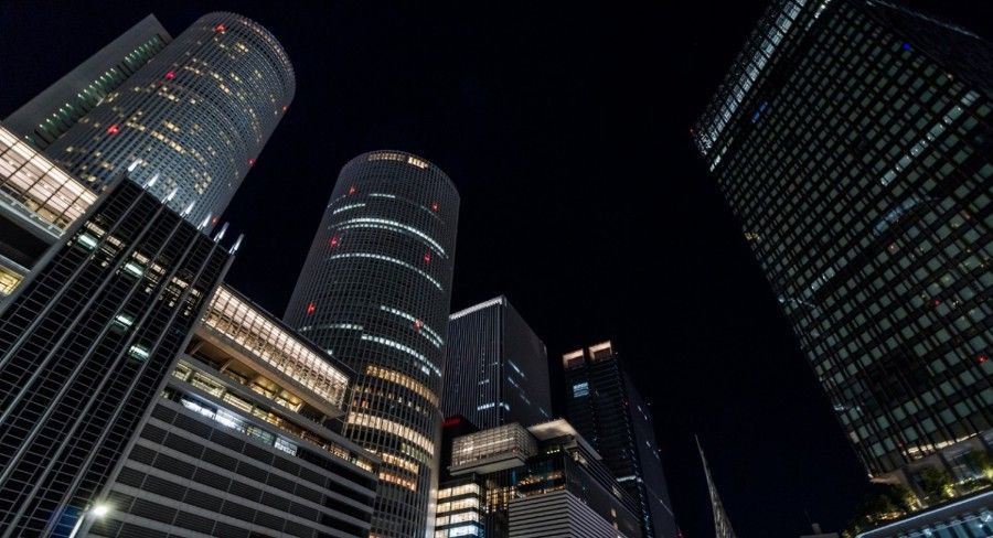 Night view of illuminated JR Central Towers in Nagoya against a dark sky.