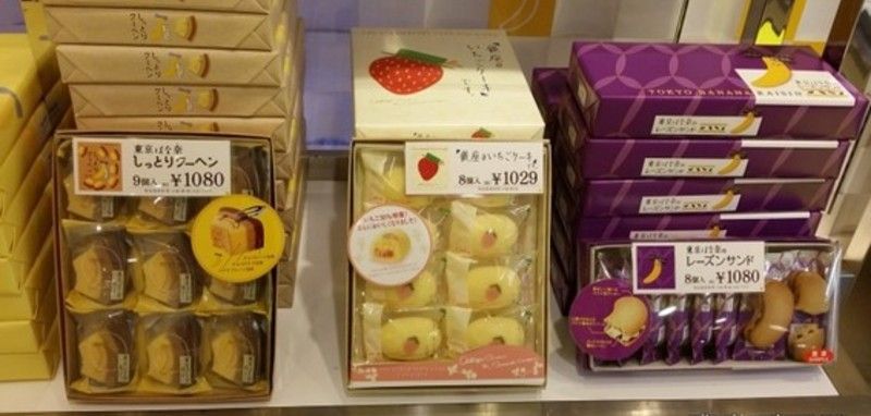 Shelves with boxes of Japanese pastries, including cake slices, strawberry desserts, and banana-shaped cookies.