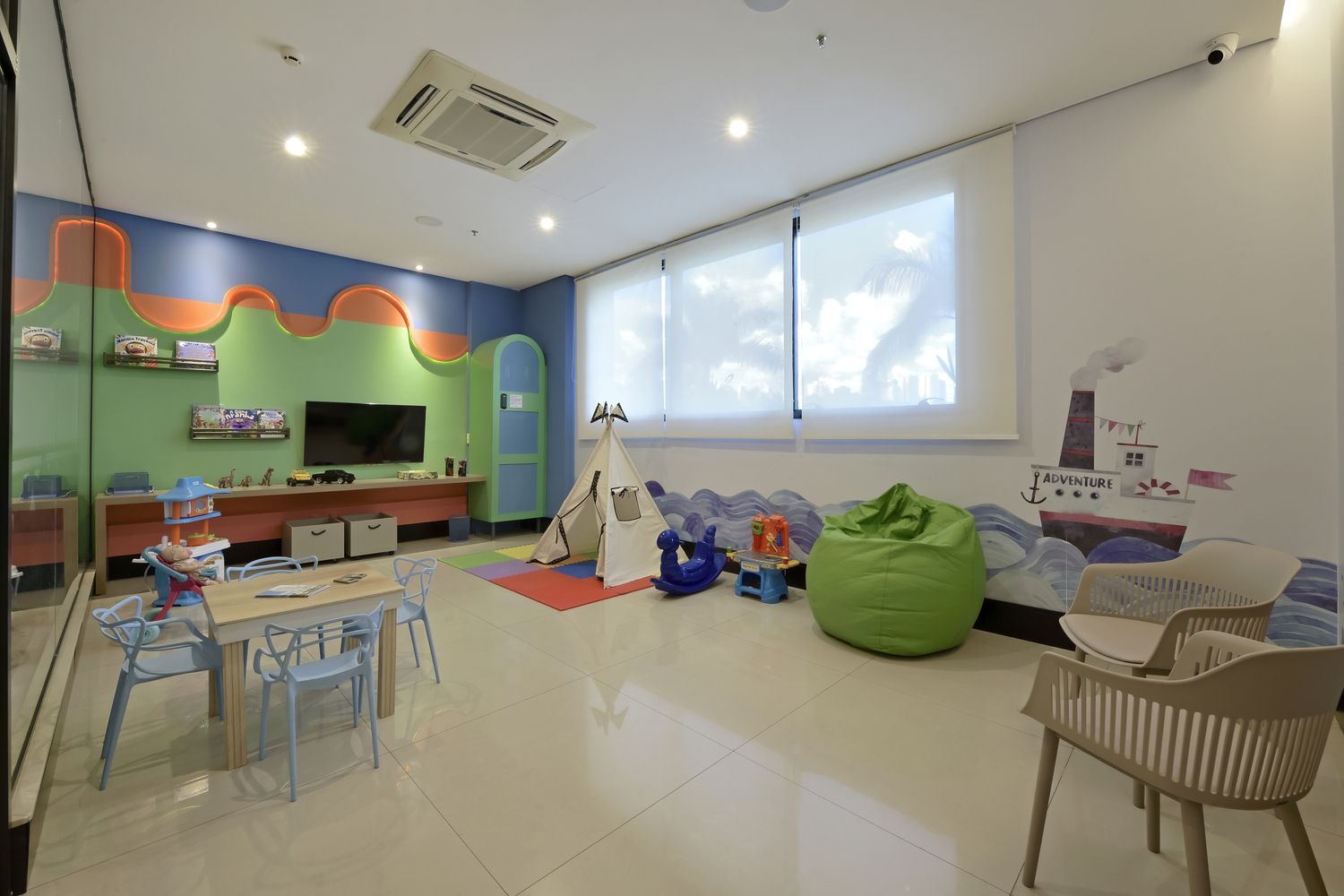 Um quarto infantil com mesa, cadeiras e televisão.