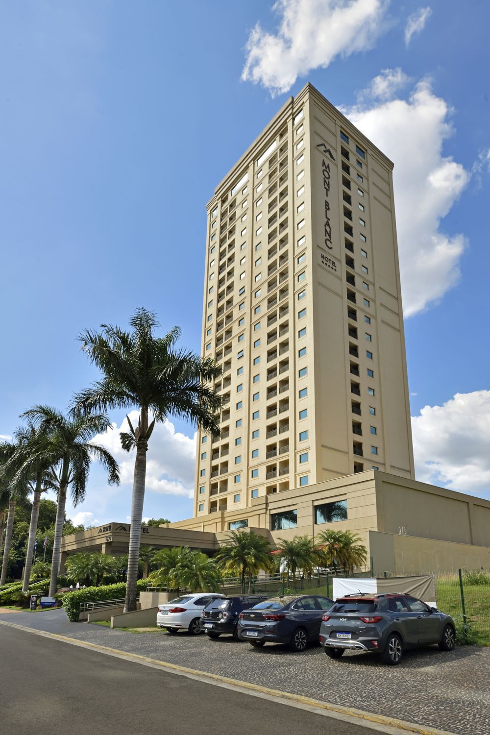 Um prédio alto com carros estacionados na frente dele.