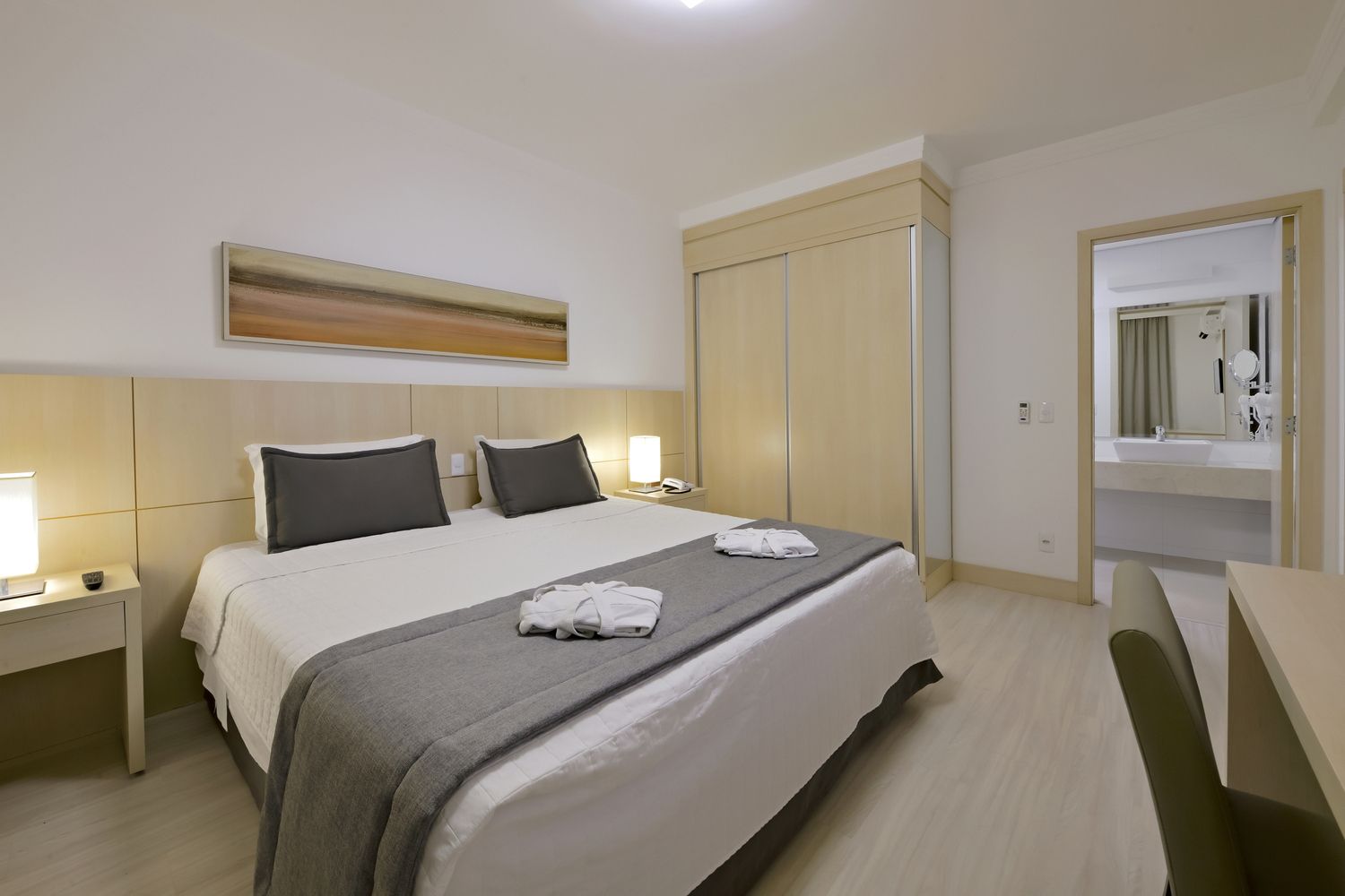 Um quarto de hotel com duas camas, uma escrivaninha e uma televisão.