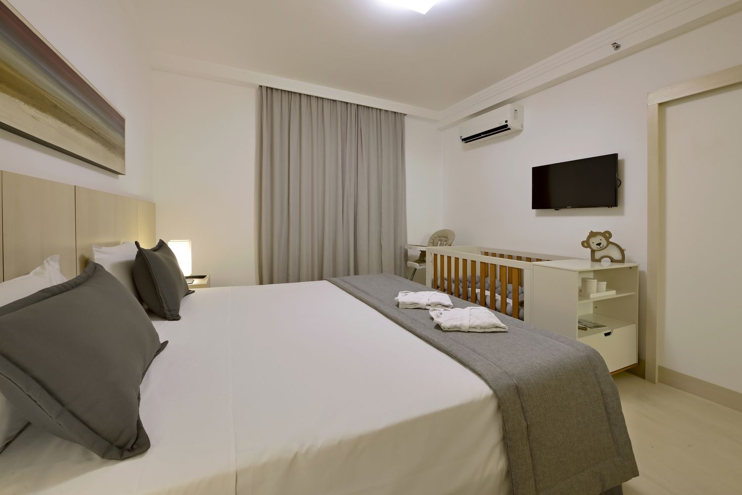 Um quarto de hotel com uma cama king size, escrivaninha e televisão.