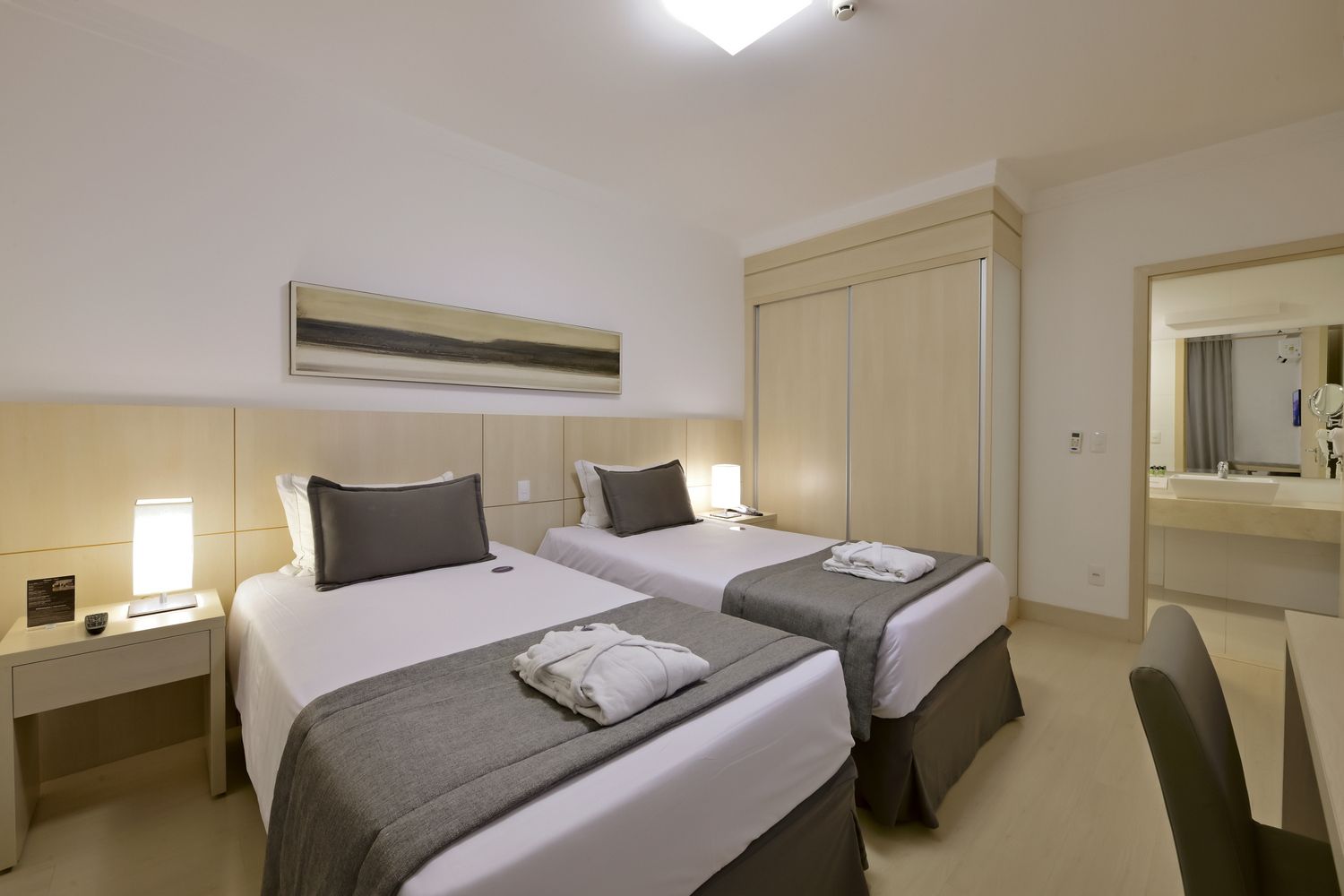 Um quarto de hotel com uma cama king size, televisão, escrivaninha e cadeiras.