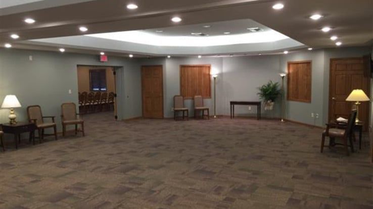 an empty room with chairs , lamps , and a table .