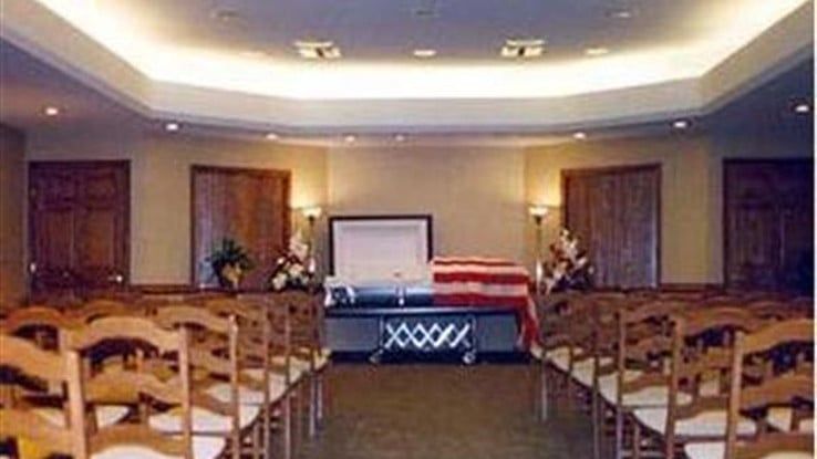 a funeral home with rows of chairs and a coffin in the middle of the room .