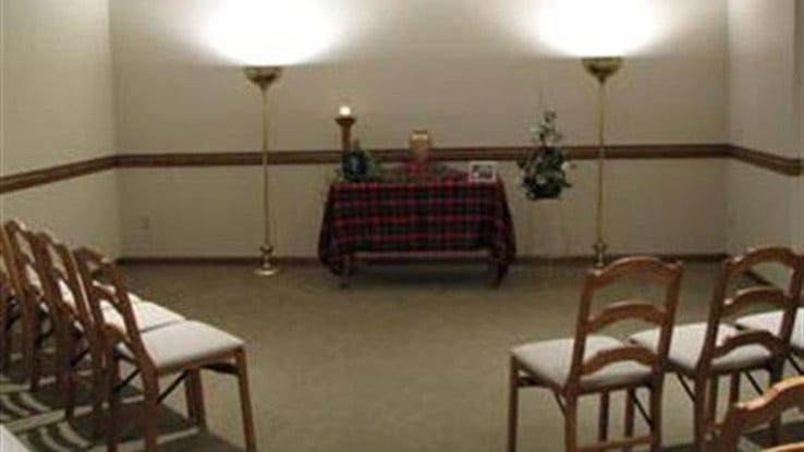 a room with chairs and a table in the middle of it .