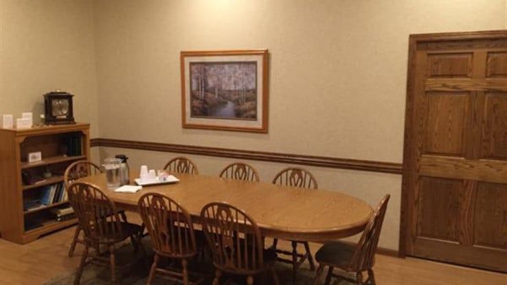 a conference room with a table and chairs and a picture on the wall .