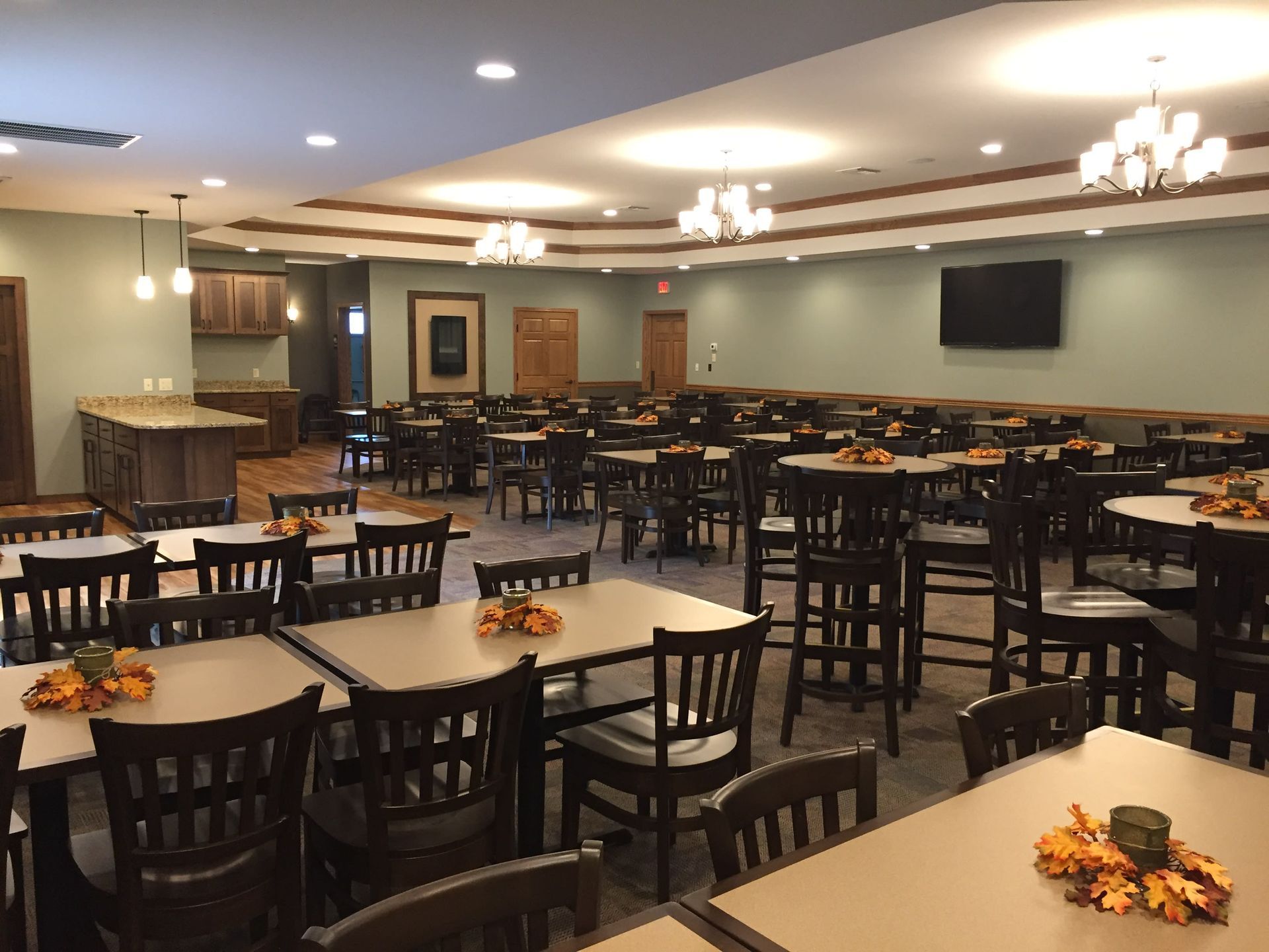 a large dining room with tables and chairs and a flat screen tv