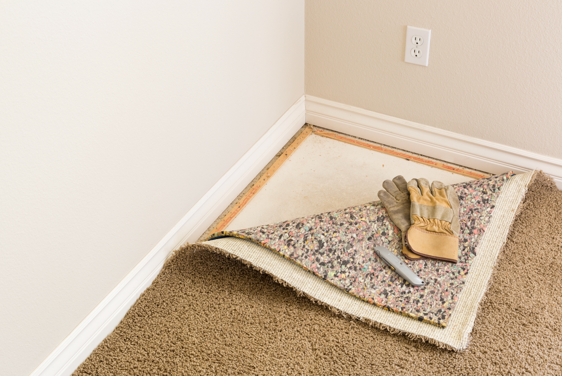 A piece of carpet is laying on the floor next to a pair of gloves.