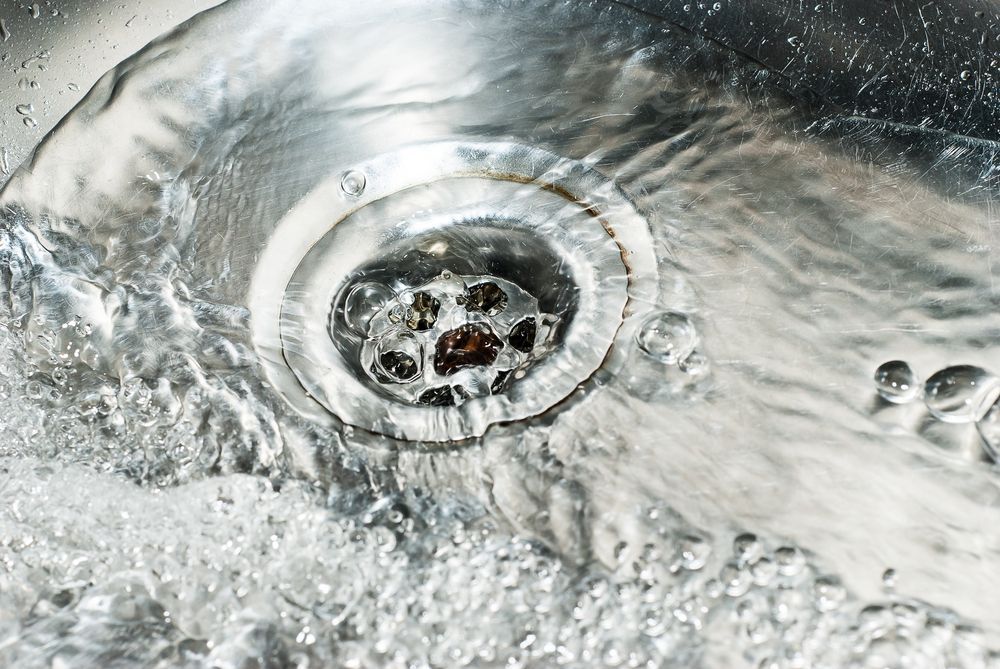 Water Flowing Down a Stainless Steel Sink Drain — Waves Plumbing in Lake Macquarie, NSW