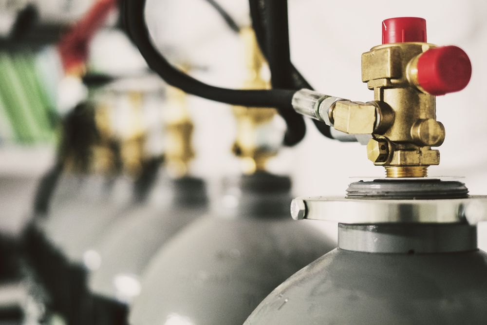 Gray Gas Cylinders With Brass Valves and Red Caps — Waves Plumbing in Wyong, NSW