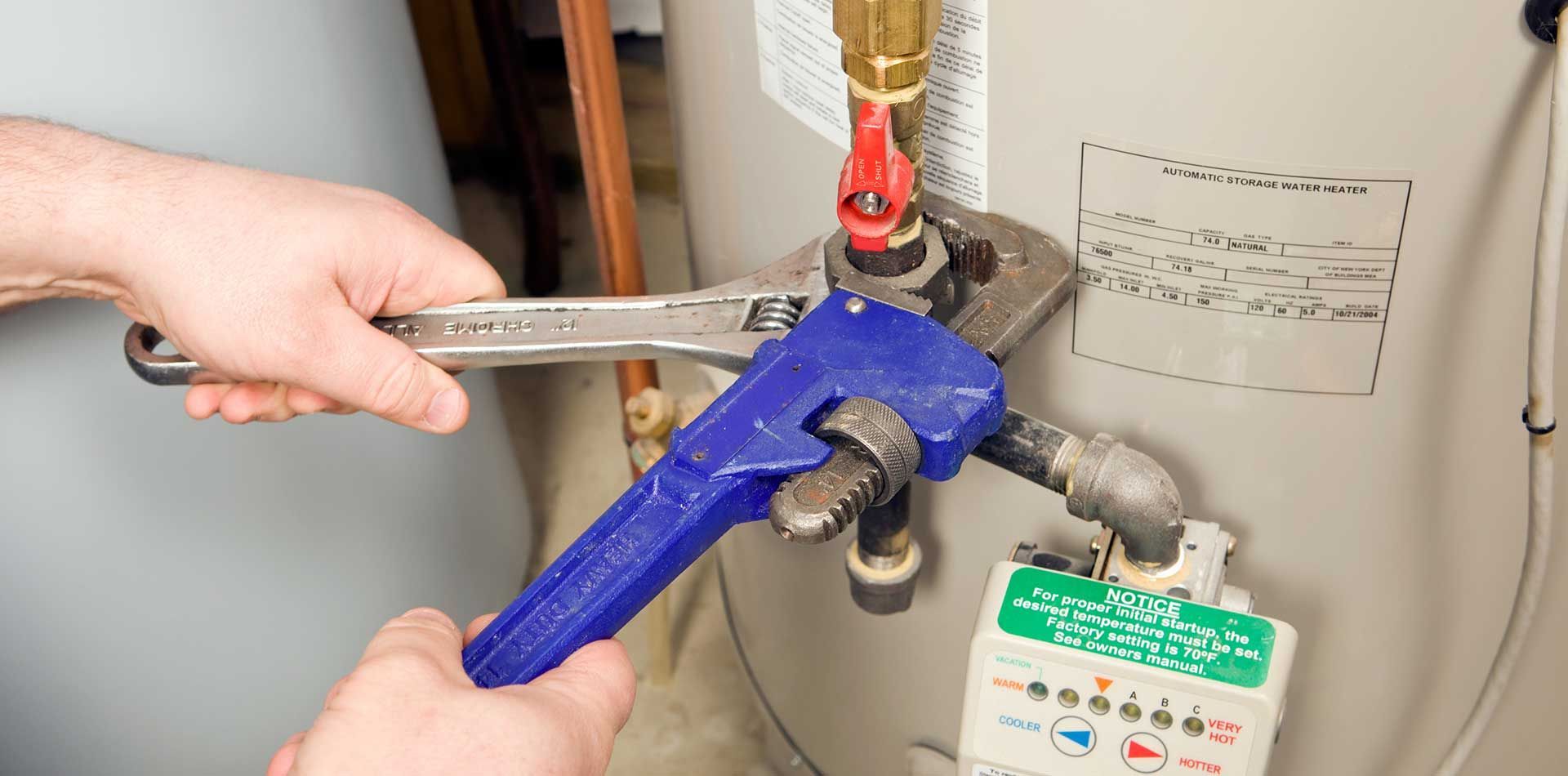 A Person Use Wrenches on Water Heater Pipes — Waves Plumbing in Central Coast, NSW