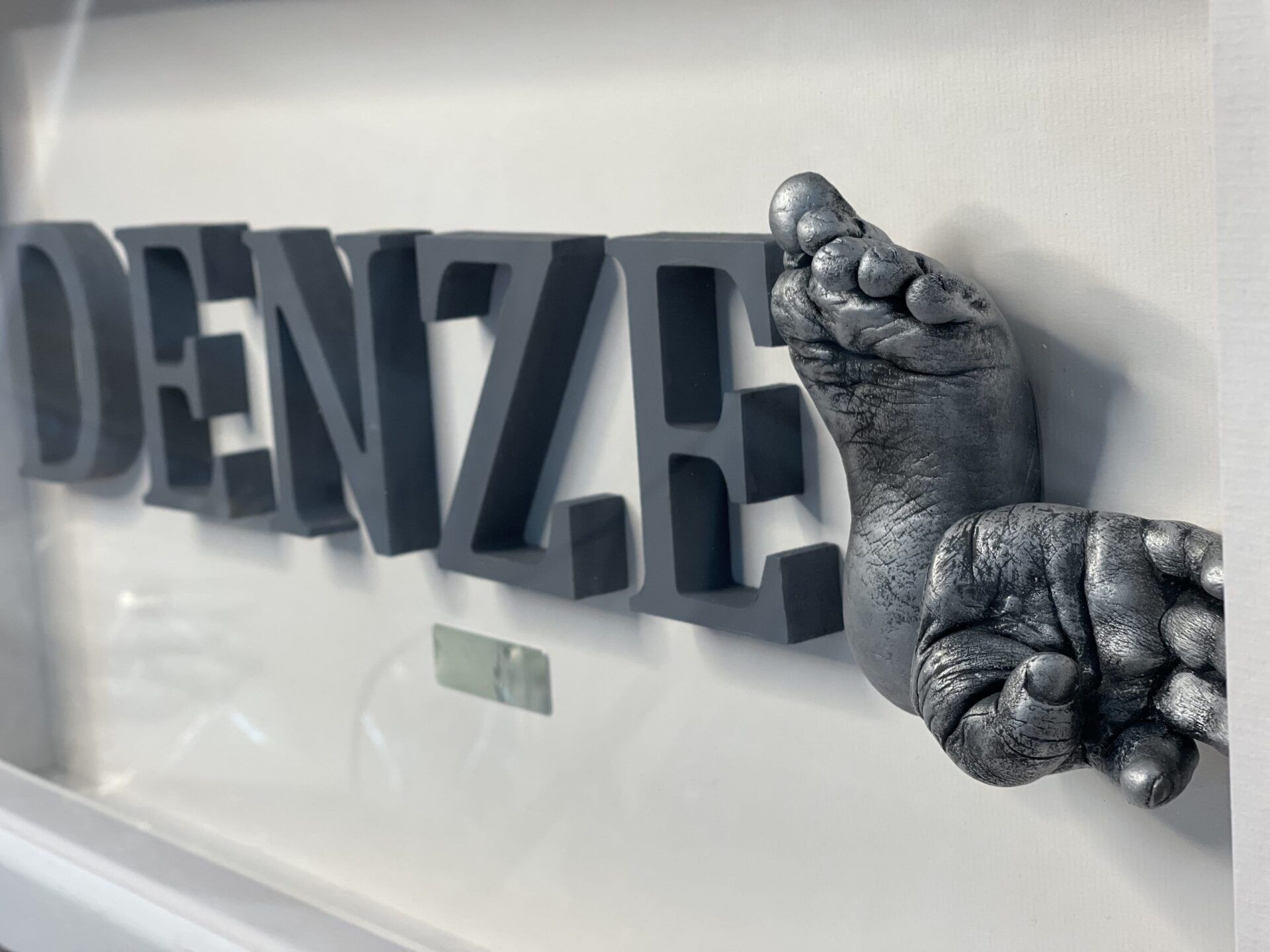 A sculpture of a baby 's foot and the name denze