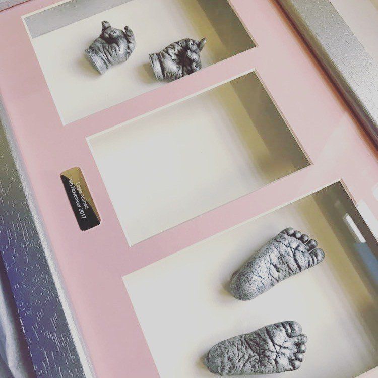 A framed picture of a baby 's hand and footprints