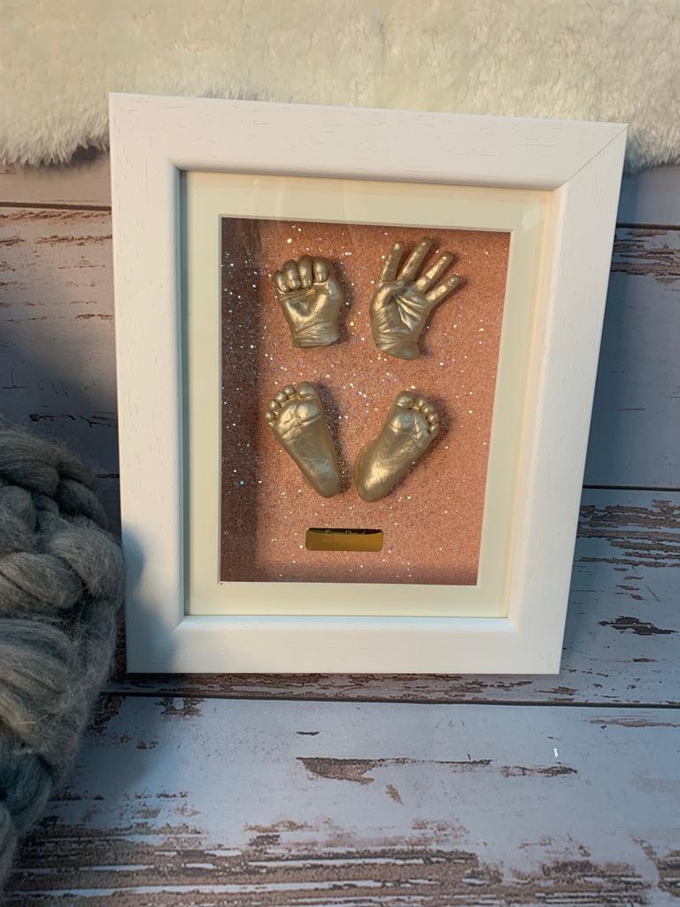 A picture of a baby 's hands and feet in a white frame.
