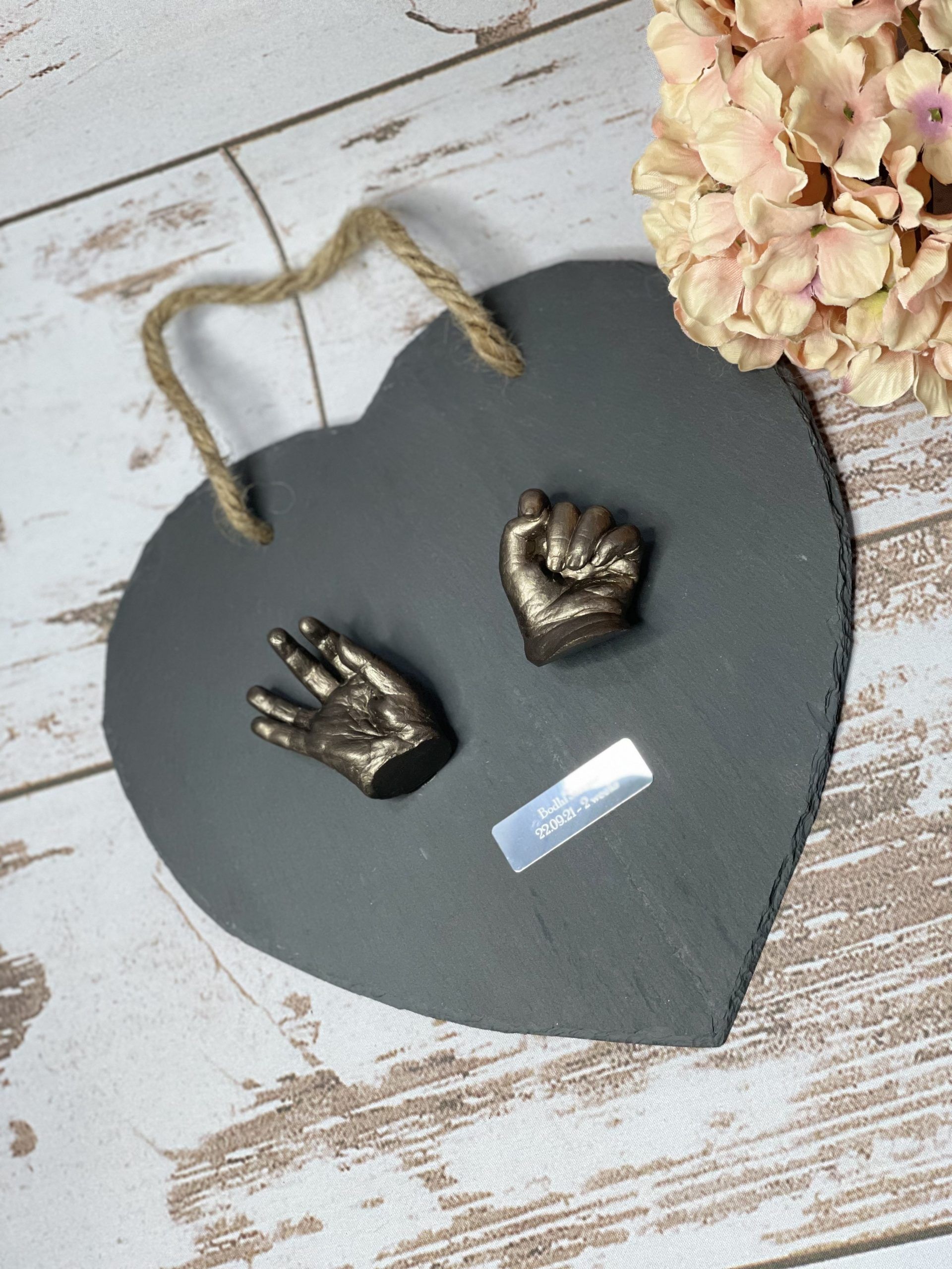 A heart shaped plaque with two hand prints on it