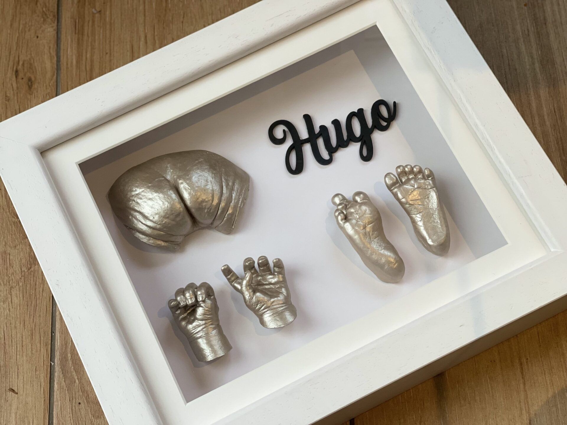 A white frame with a picture of a baby 's hands and feet