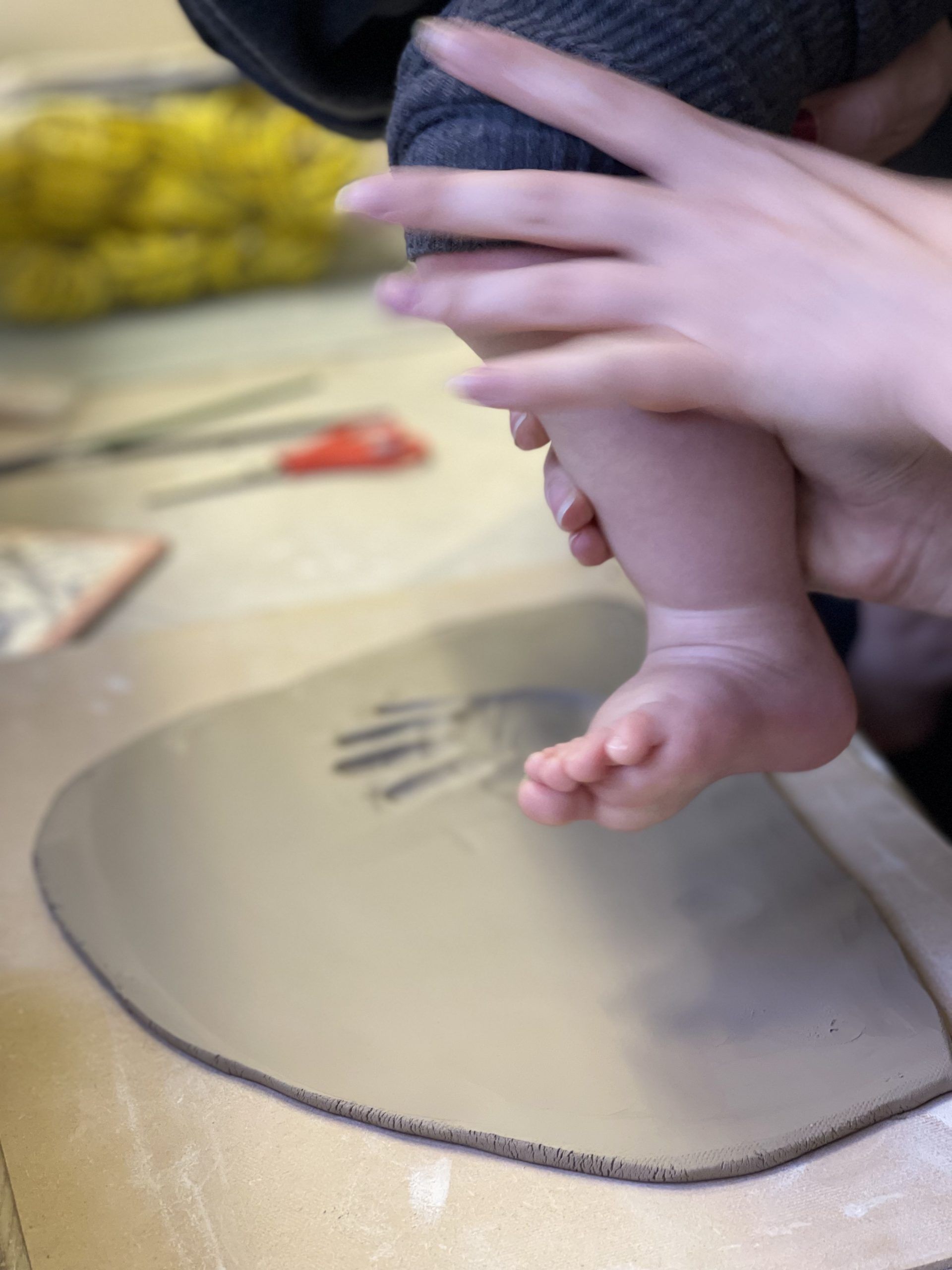 A person is holding a baby 's foot on a piece of cardboard