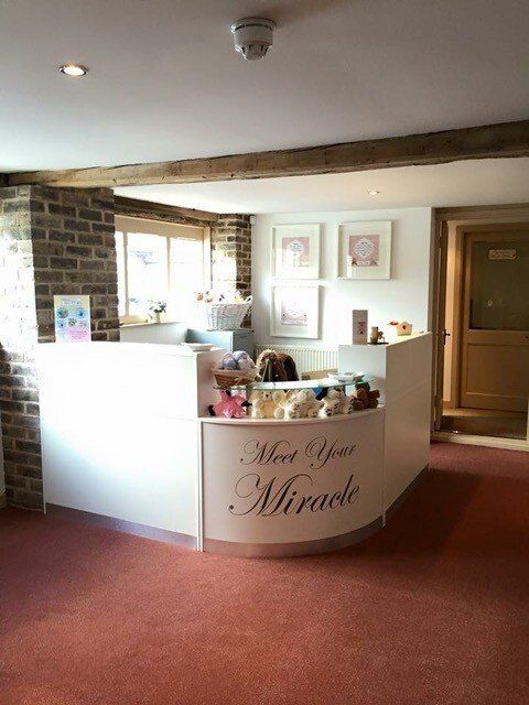 A reception desk in a room that says meet your miracle