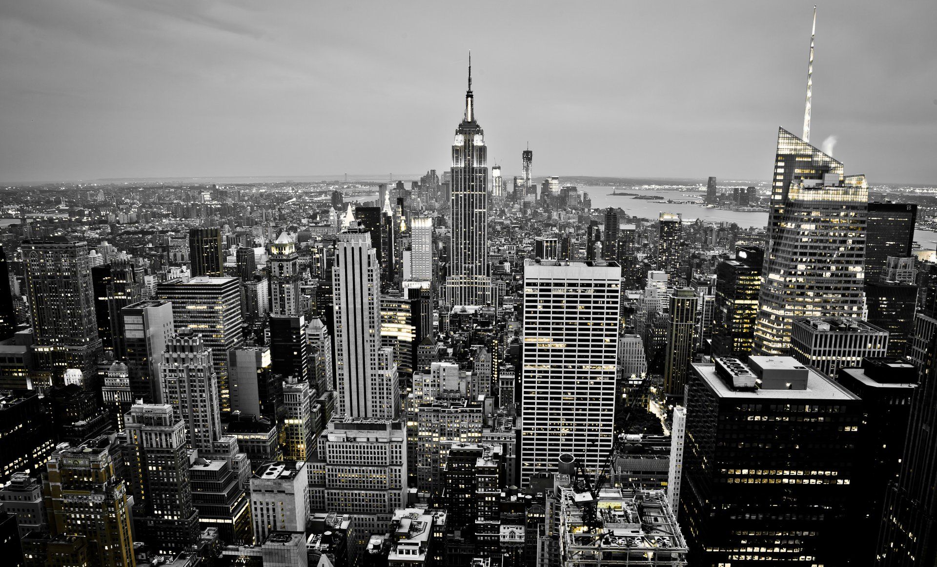 Black and white aerial view of New York City skyline at dusk, showcasing skyscrapers and the Empire State Building.