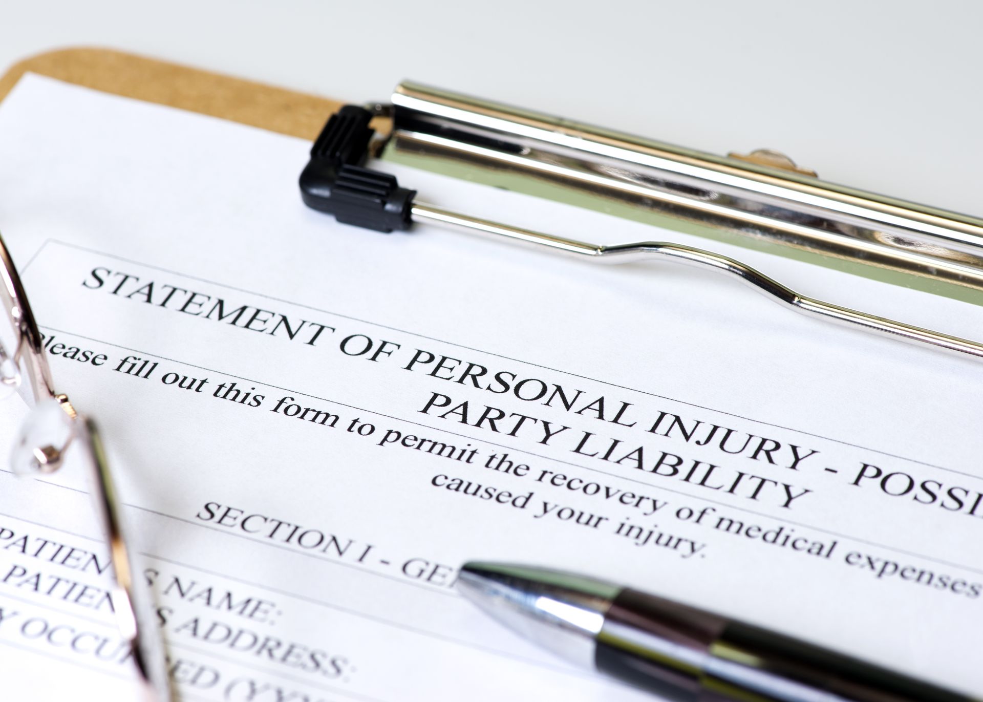 Personal injury form on a clipboard with a pen and glasses, detailing medical expenses.