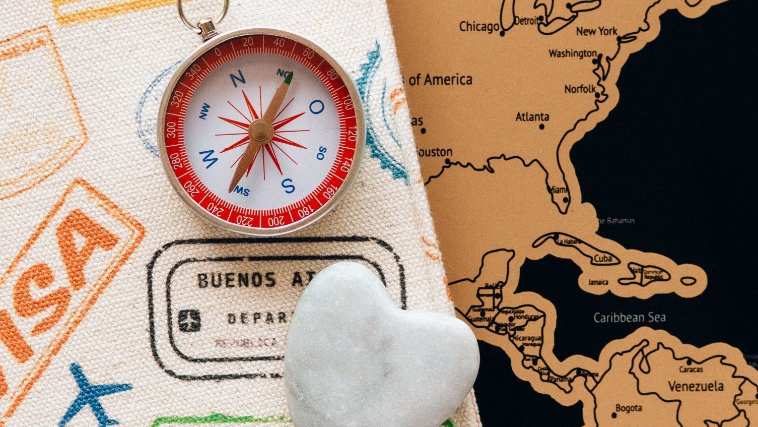 Compass on travel documents, with a map of North America, and a small heart.