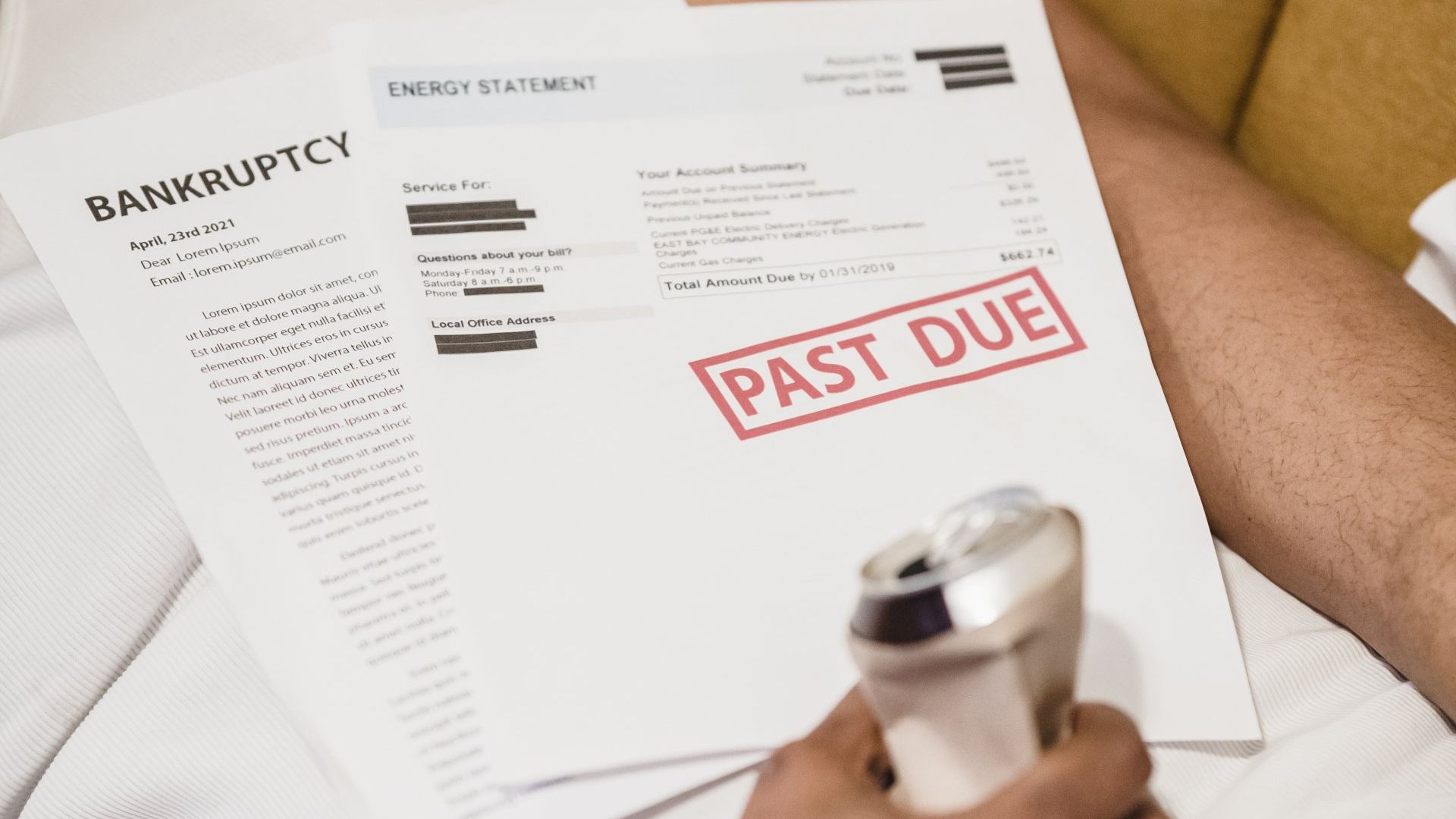 Person holding a razor with past due energy bill and bankruptcy document.