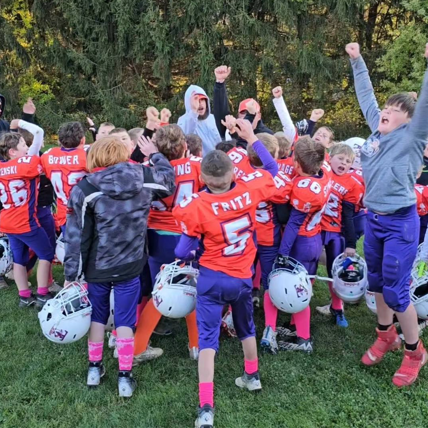Football player in silver uniform runs with ball on a green field.