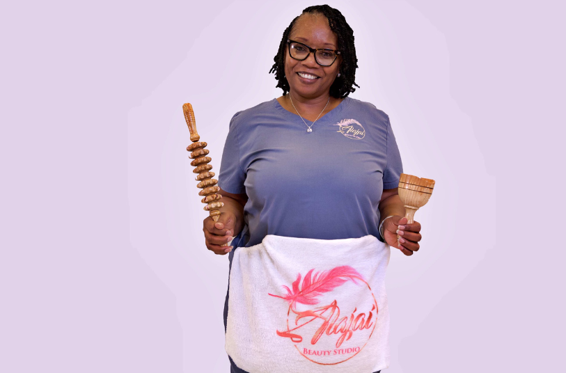 A woman is holding a wooden rolling pin and a towel.