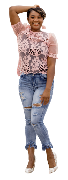 A woman wearing a pink lace top and jeans is standing on a white background.