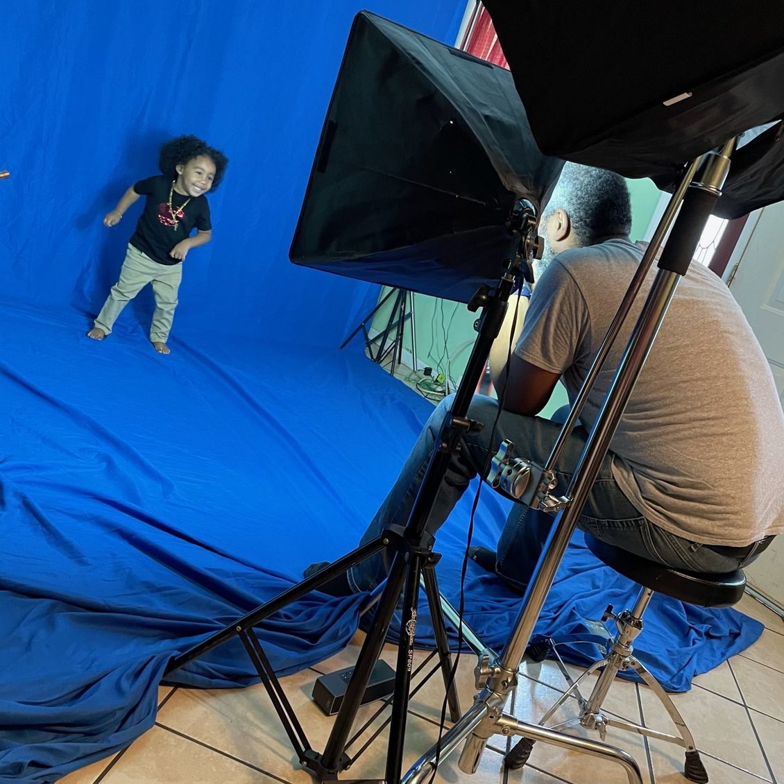 A man is taking a picture of a child in front of a blue screen