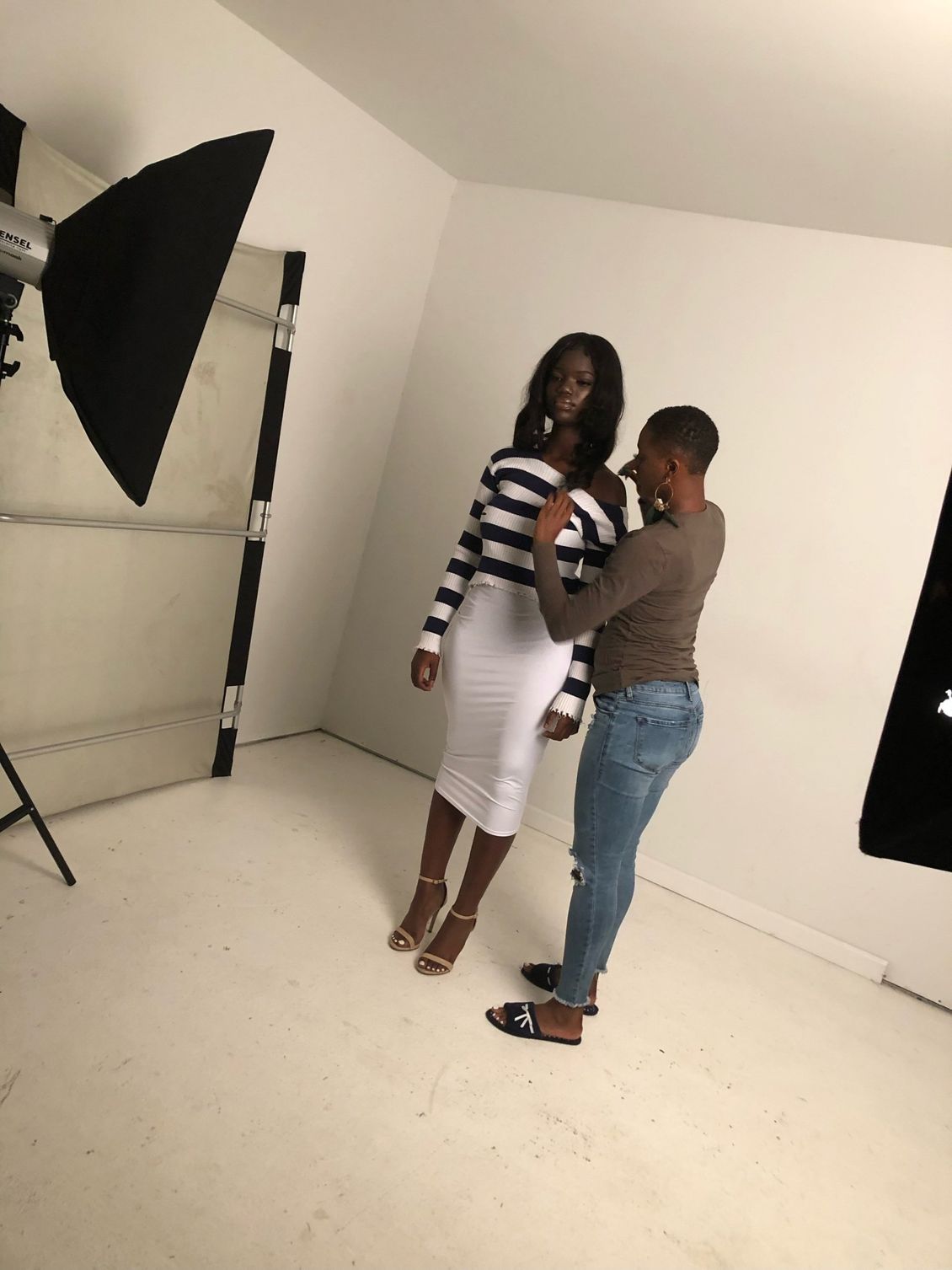 A woman in a striped top and white skirt is being photographed by a man