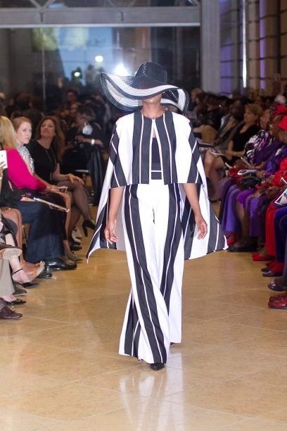 A woman is walking down a runway wearing a black and white striped outfit