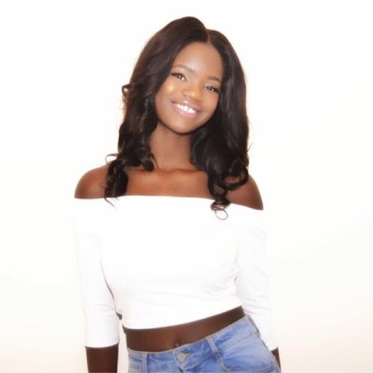 A woman wearing a white off the shoulder top and blue jeans