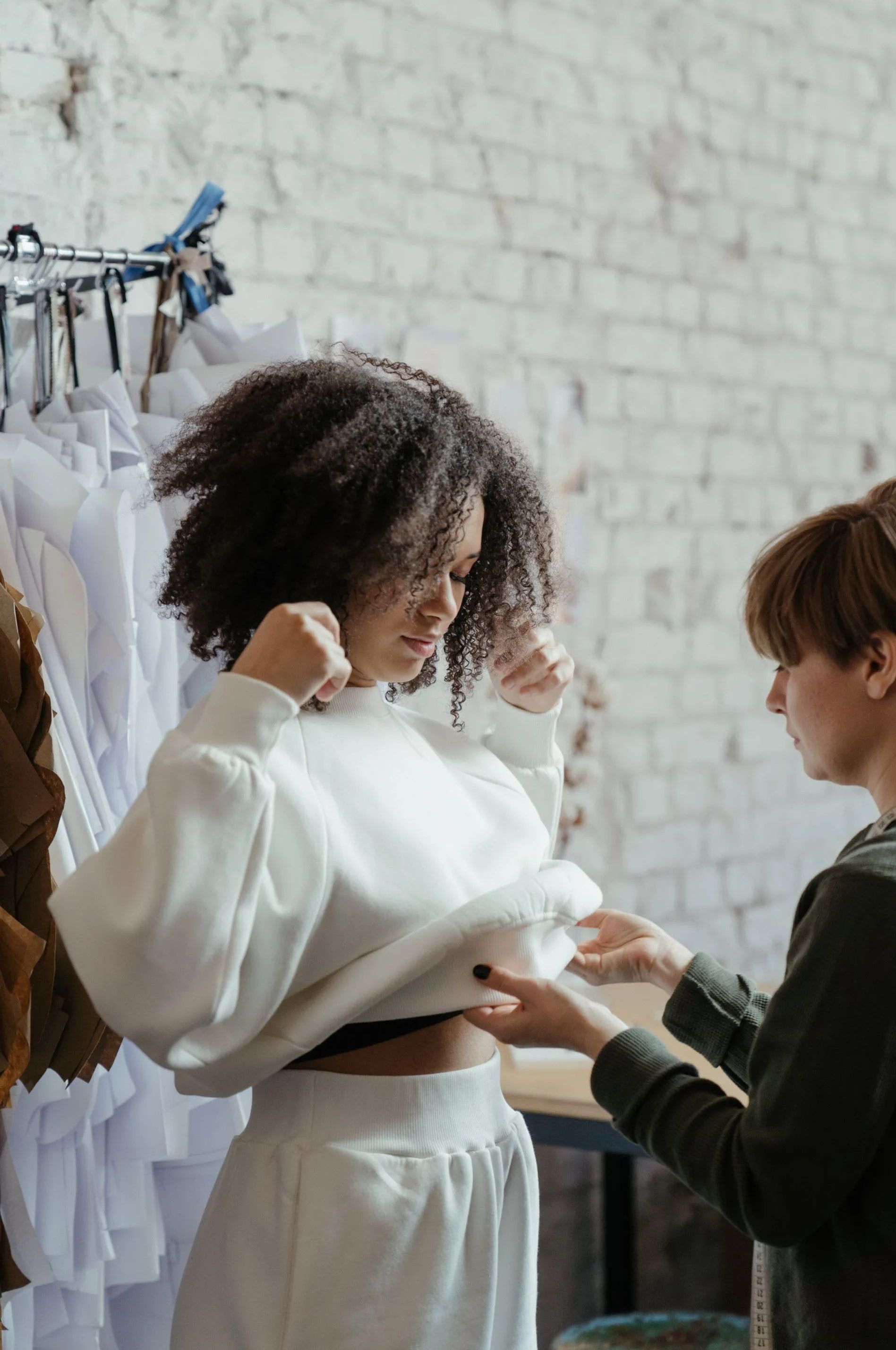 A woman is trying on a white sweater in a store.