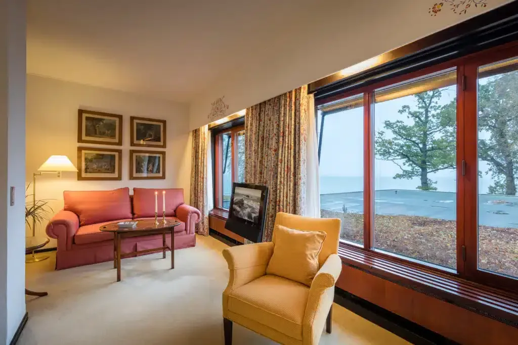 En stue med sofa, stol, bord og store vinduer.