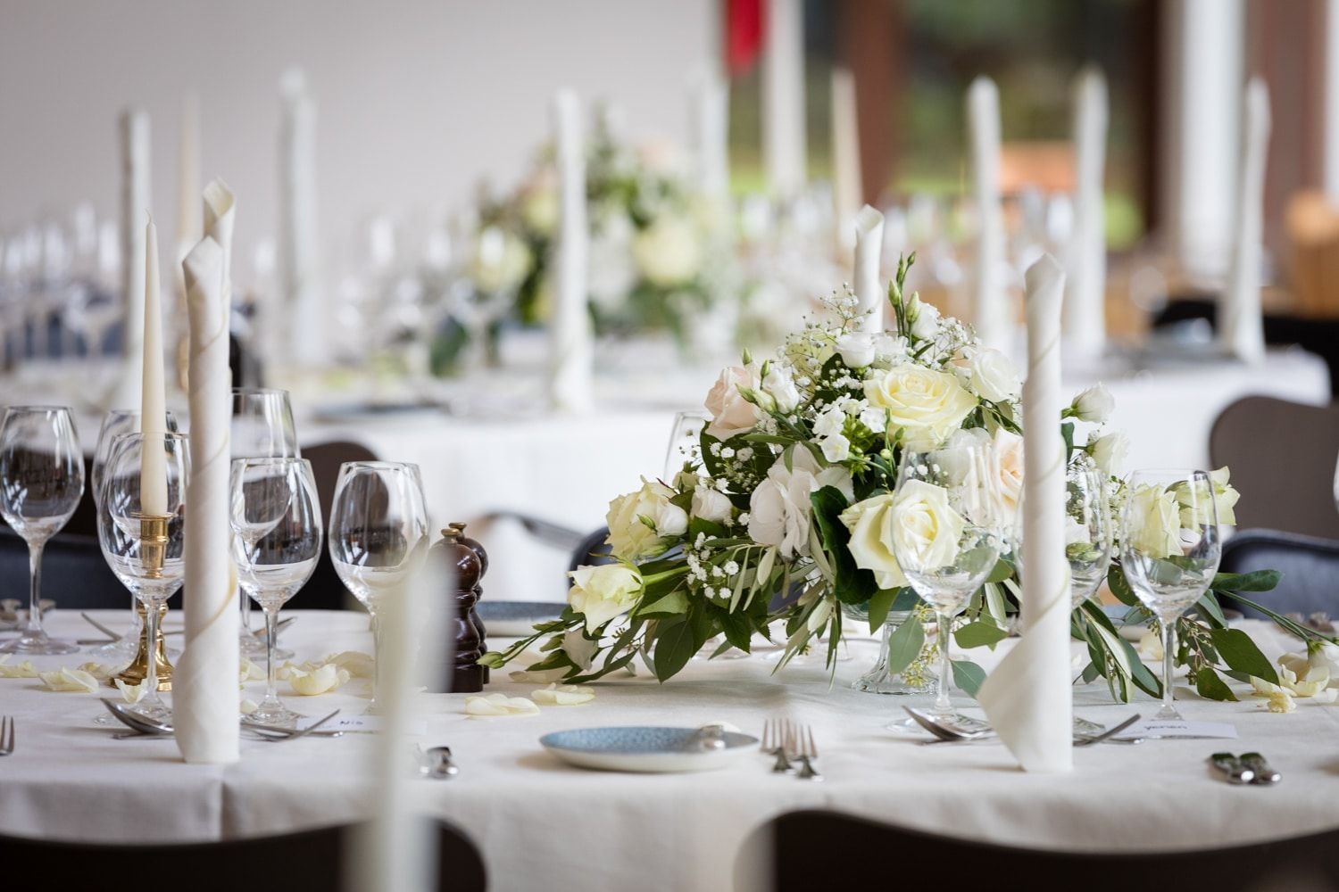 Et bord dækket til en bryllupsreception med blomster og stearinlys på.