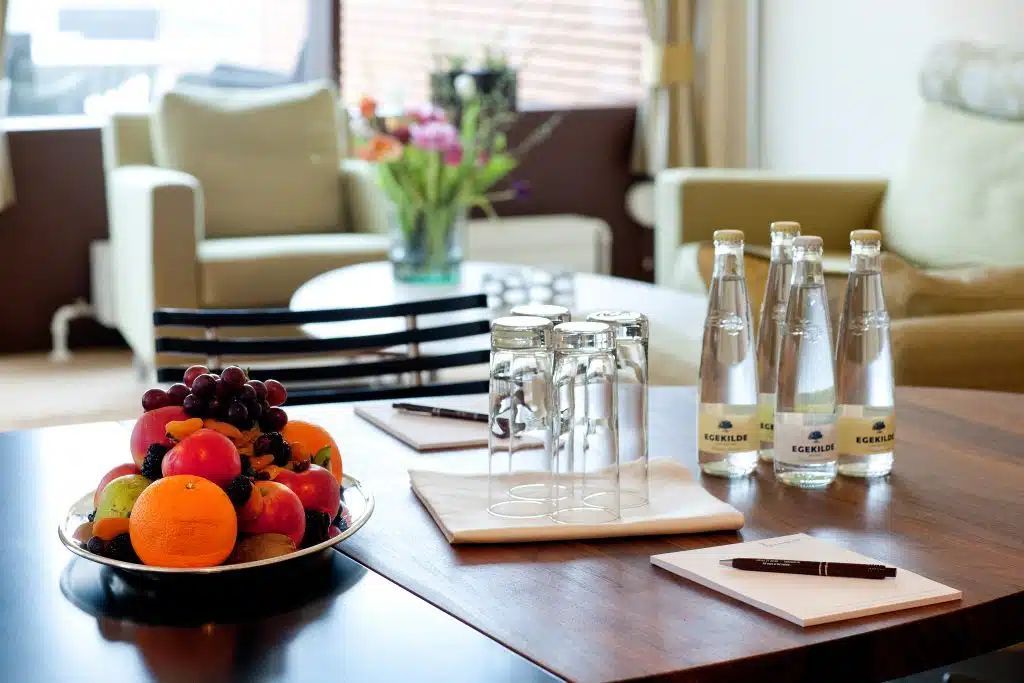 En skål frugt står på et bord ved siden af ​​flasker med vand