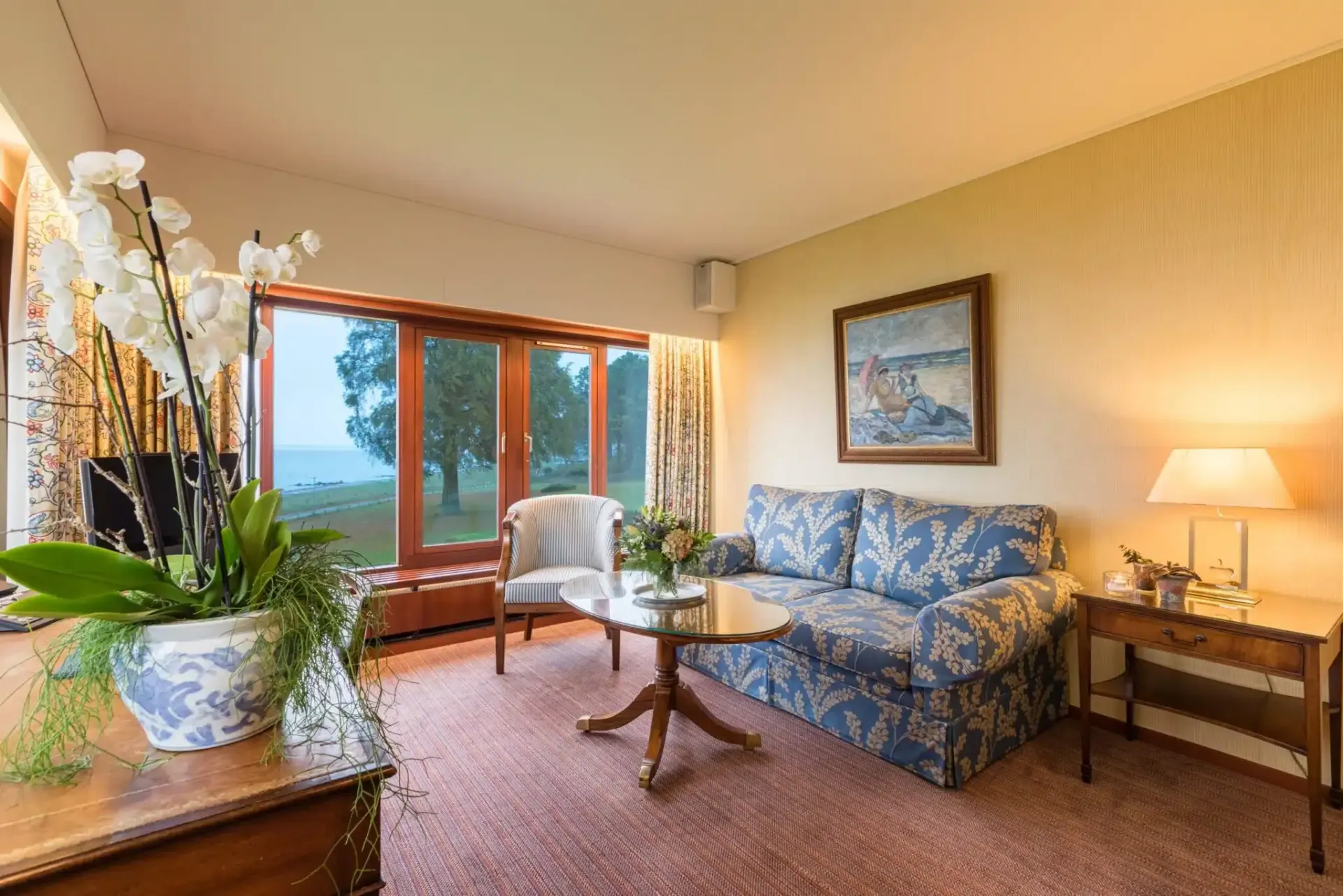 En stue med sofa, bord, stole og et maleri på væggen.