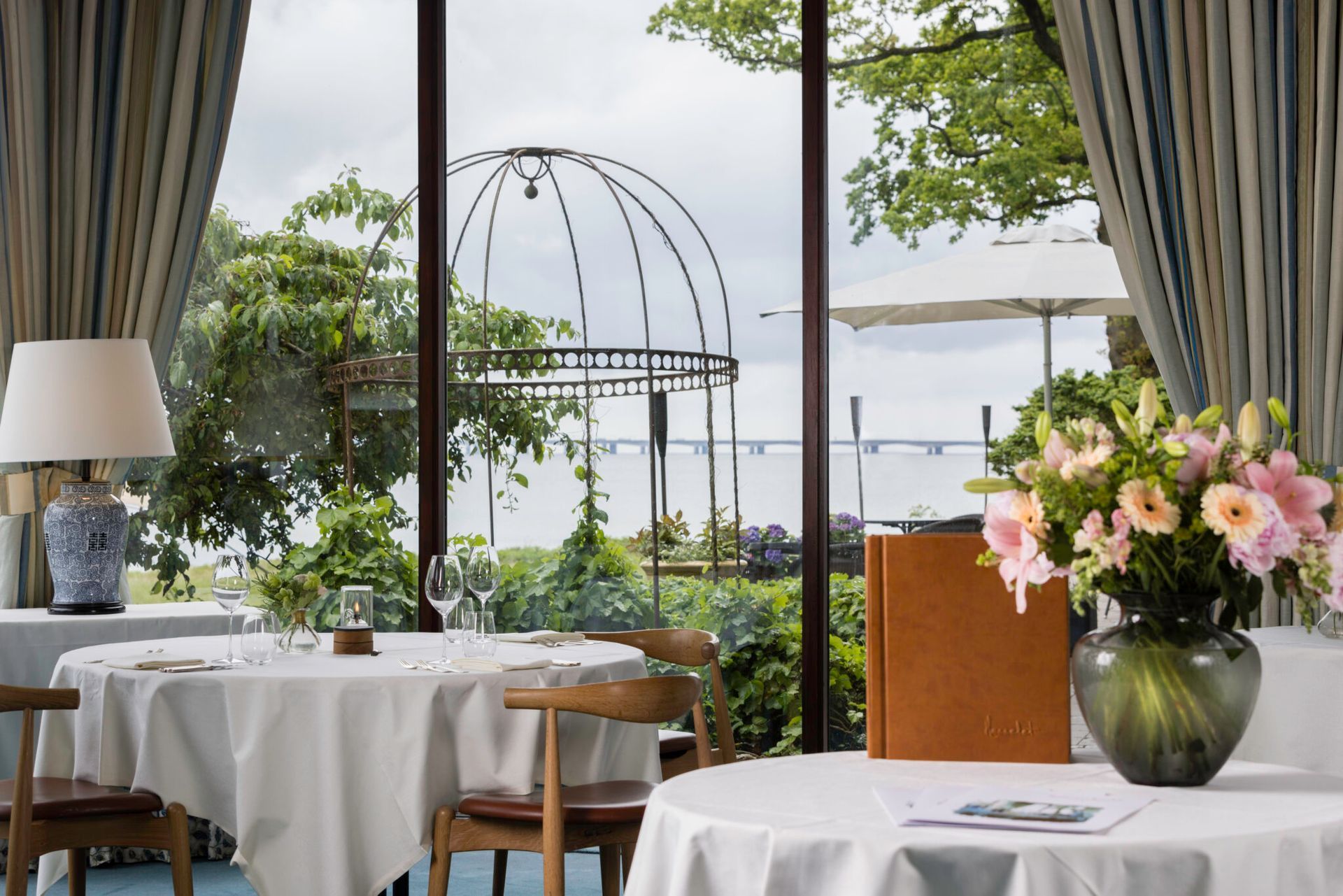 En restaurant med borde og stole og en vase med blomster på bordet.