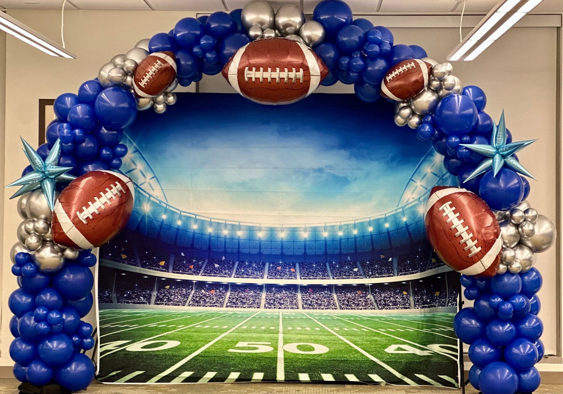 A balloon arch with a picture of a football field in the background.
