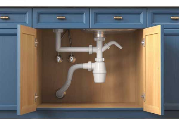 A sink is under a cabinet in a kitchen with the doors open.